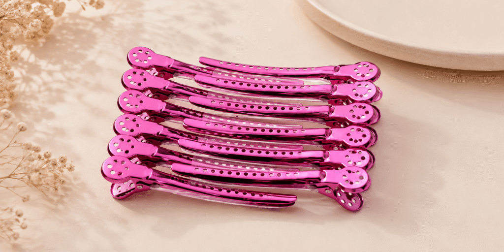 Pink metal hair clips with perforated details arranged in a neat stack