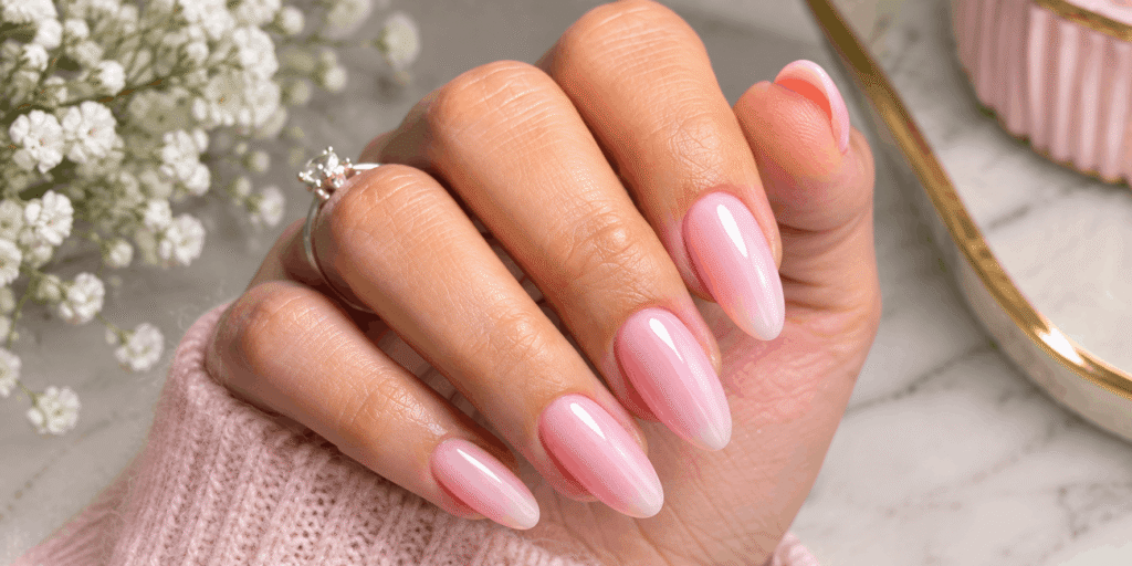 Glossy pale pink almond-shaped nails with a delicate sparkling ring